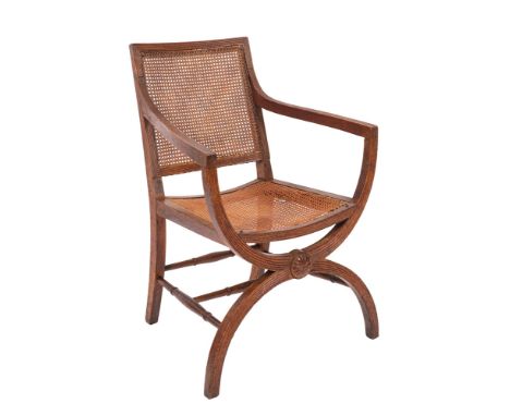 A 19th Century oak curule armchair after a design by Thomas Hope having a cane panel back and seat, the reeded frame with ros