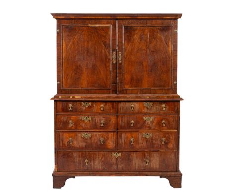 An early 18th Century walnut cabinet on chest, the upper part with a moulded cornice, enclosed by a pair of moulded panel doo