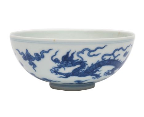 A Chinese blue and white porcelain bowl the exterior painted with a pair of dragons amongst clouds, the interior with a singl