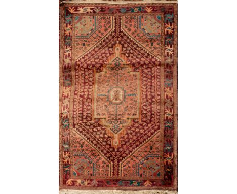 A Turkish rug,  the pink filed with a central shaped lozenge pole medallion in pistachio and pastel shades enclosed by a loze