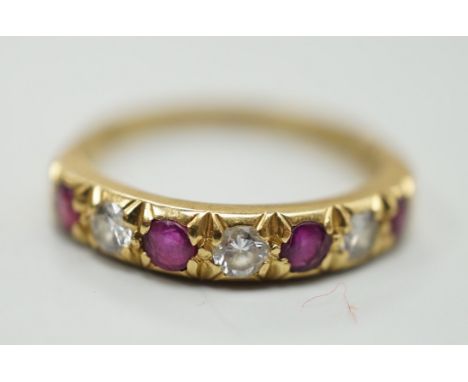 A modern 18ct gold, four stone ruby and three stone diamond set half hoop ring, size L/M, gross weight 3.1 grams.