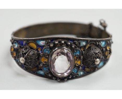 An early to mid 20th century continental white metal polychrome enamel and foil backed oval cut rock crystal set hinged bangl