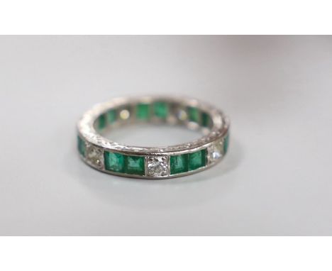 A mid 20th century 18ct white metal, emerald and diamond set full eternity ring(a.f.), size M/N, gross weight4.9 grams.