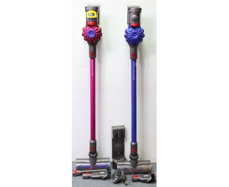 Two Dyson stick vacuum cleaners with various accessories.