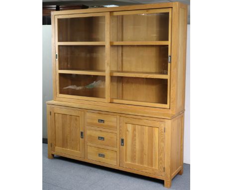 A light oak tall wall unit the upper part fitted two open shelves enclosed by a pair of glass sliding doors, the base fitted 