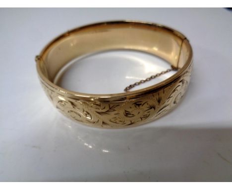 An engraved gold plated hinged bangle