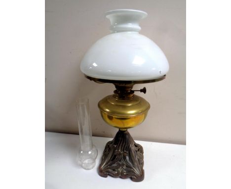 A brass oil lamp on metal base, with opaque glass shade 