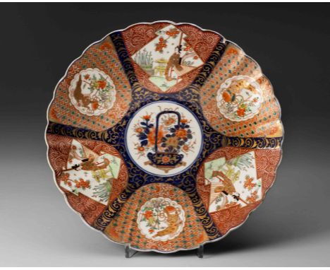 Circular with a scalloped edge, the centre painted with a flower-filled basket, enclosed by six panels alternating with Shi-S