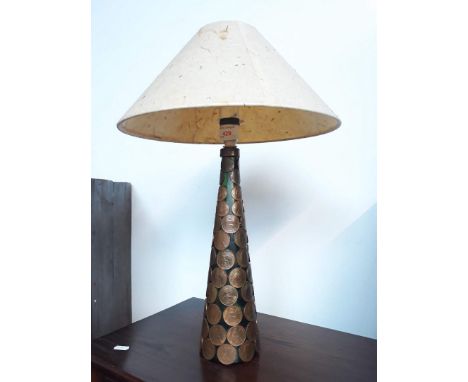 A glass lamp decorated with pennies. 