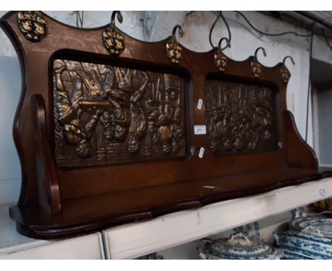 A coat and hat rack with ornated brass plaques 