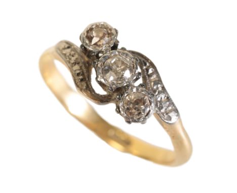 A THREE STONE DIAMOND RING illusion-set on an 18ct yellow gold shank with cross-over shoulders, ring size N