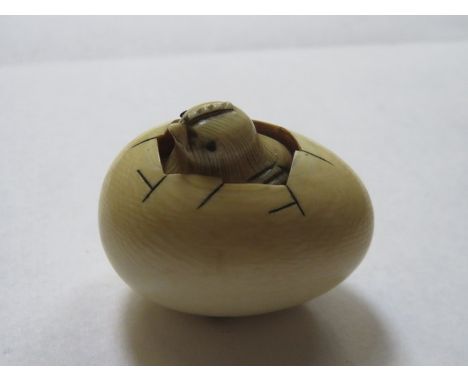 HEAVILY CARVED ORIENTAL IVORY NETSUKE OF A CHICK HATCHING FROM AN EGG, SIGNED TO THE BASE