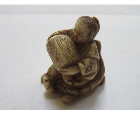 HEAVILY CARVED ANTIQUE IVORY NETSUKE DEPICTING A SEATED GENT ON TURTLE