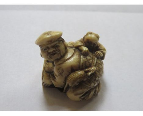 HEAVILY CARVED ANTIQUE IVORY NETSUKE A FIGURE GROUP SIGNED TO BASE,