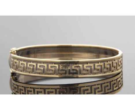 A 9ct Greek key decorated hinged bangle, the two tone bangle with textured background and raised Greek key decoration and bor