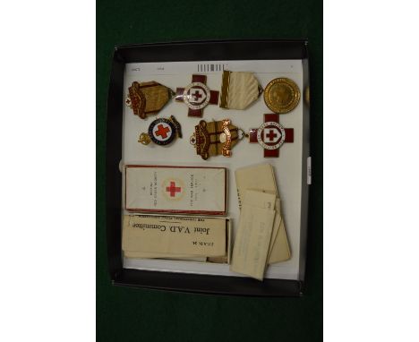 A collection of four enamel and gilt metal Red Cross nursing badges together with associated paperwork.