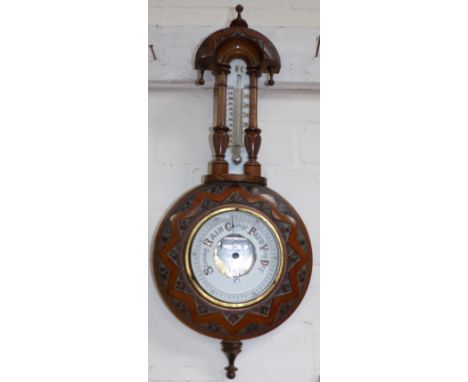 A carved walnut circular barometer with thermometer
