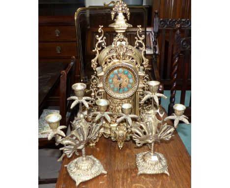 A reproduction continental brass cased clock with a pair of figural candelabra; a brass mounted smoked glass firescreen