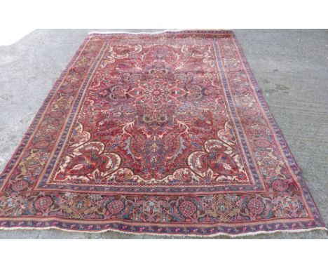 A Middle Eastern carpet with central medallion on red ground, multi-bordered and fringed, 11 ft. x 8 ft.