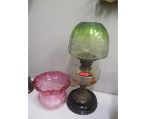 A Victorian oil lamp with a clear glass reservoir and a green and clear glass shade and a cranberry and clear glass shade 