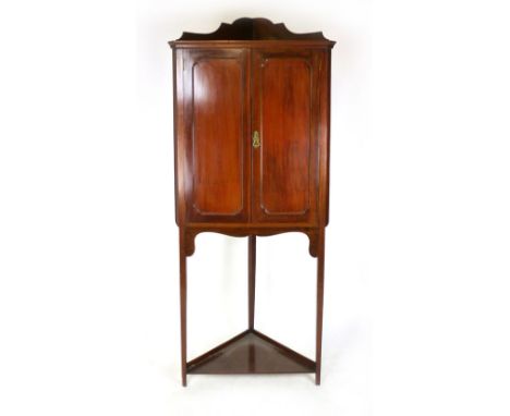 A mahogany floor standing corner cupboard, late 19th century, pair of panelled doors enclosing shelving above a shelf stretch