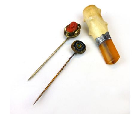 Two tie pins, one mounted with a millifiori panel, the other with a carved coral plaque; together with a silver mounted cigar