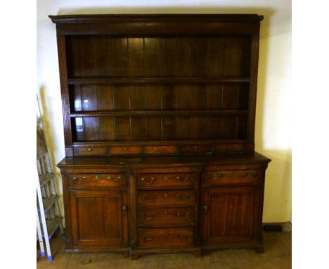 A George lll and later oak breakfront dresser, later 18th century, the later two shelf plate rack with five spice drawers on 