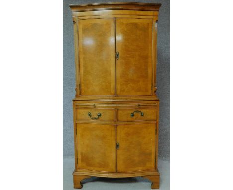 A Georgian style burr walnut tallboy cabinet with internally lit upper section above frieze drawers above two further panel d