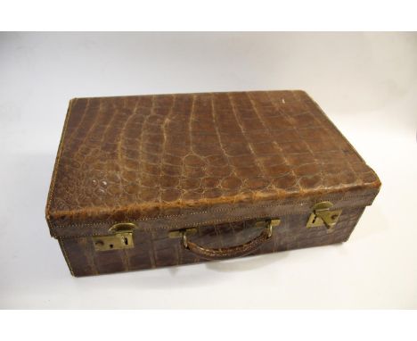 CROCODILE SKIN SUITCASE the case with brass lock plates and hinges, and with a material lined interior (case 56cms by 35cms).