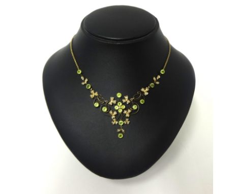 A Victorian gold, peridot and half pearl set necklace, the graduated openwork scroll front milligrain collet set with mixed c