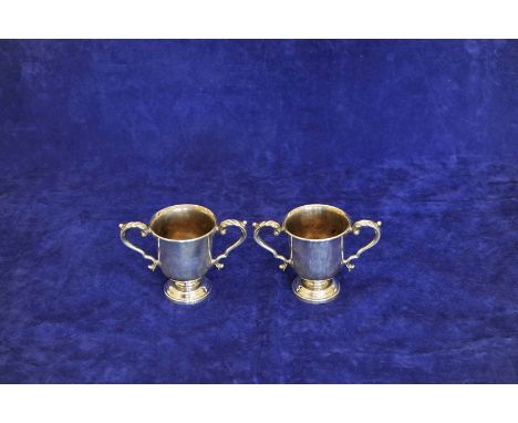 A pair of Elizabeth II silver twin handled cups with acanthus leaf capped scrolled handles, on circular stepped feet. London 