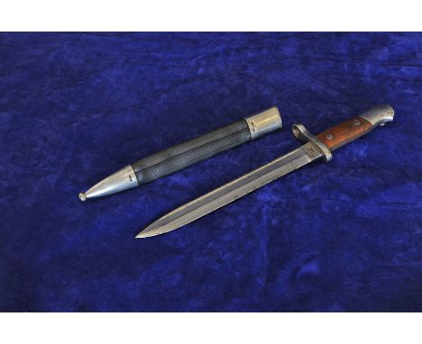 A Spanish bayonet with wooden handle and black leather white metal mounted scabbard. The 10ins blade engraved Artilleria FCA 