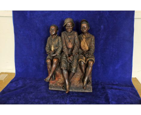 A Goldscheider figural group entitled 'Les trois enfants noir'. 23ins by 14ins depicting three youths seated on a brick wall.