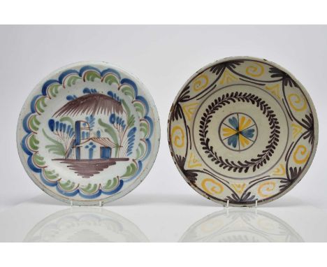 An English delftware charger, 18th century, painted in polychrome with a building to the centre and a wave border to the rim,