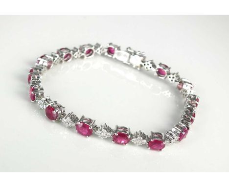 An 18ct white gold ruby and diamond bracelet, designed as sixteen oval mixed cut rubies each interspersed with a diamond shap