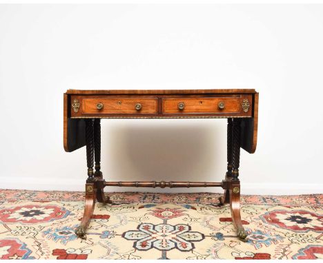 A Regency brass inlaid rosewood sofa tableThe hinged rectangular top with rounded corners, fitted with two frieze drawers ope