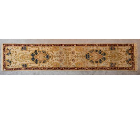 An Agra runner with central palmettes and scrolling floral design on a cream ground within a floral border. L.342x76cm 