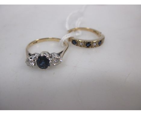 A three stone sapphire and diamond ring; the central oval sapphire, claw mounted with a round brillinat cut diamond to either