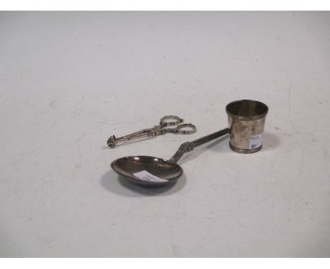 A silver serving spoon, scissor action sugar nips and a spirit tumbler  