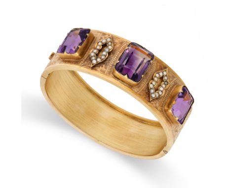AN ANTIQUE AMETHYST AND PEARL BANGLE in yellow gold, set with three cushion cut amethysts accented by pearls and engraved mot