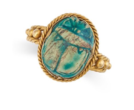 AN EGYPTIAN REVIVAL SCARAB BEETLE RING in yellow gold, the face set with a carved scarab, the band of twisted wirework design