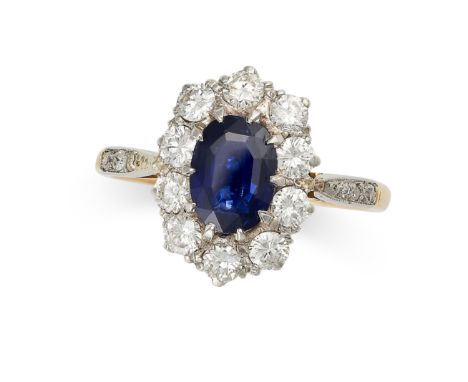 A SAPPHIRE AND DIAMOND CLUSTER RING in 18ct yellow gold and platinum, set with an oval cut blue sapphire of 1.36 carats withi