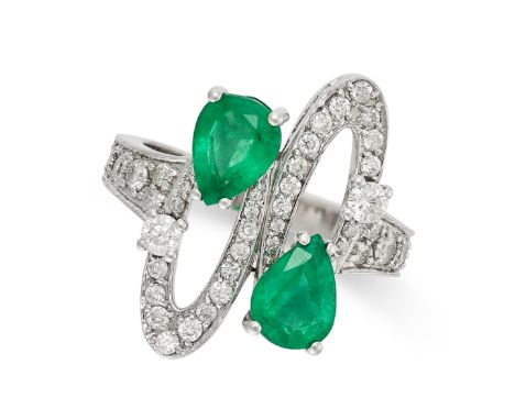 AN EMERALD AND DIAMOND DRESS RING in 18ct white gold, in crossover design, set with two pear cut emeralds and round brilliant