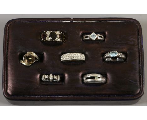 A ring pad containing seven silver rings including amethyst and garnet set examples.