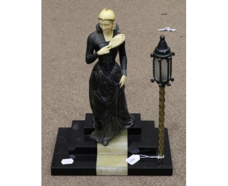 An Art Deco Style Spelter and Ivorine Figure of a Lady, in flowing dress, on a stepped marble base with a Venetian lamp, sign