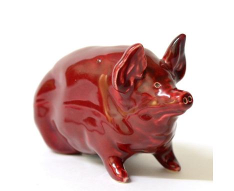 A Wemyss Pottery Figure of a Small Pig, early 20th century, decorated with a ruby coloured glaze, impressed marks, 16cm long