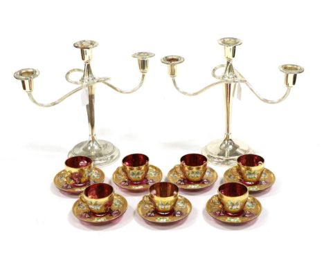 A Set of Seven Bohemian Ruby Glass Coffee Cups and Saucers, early 20th century, painted with flower sprigs on a gilt scroll g