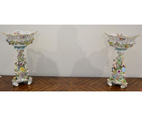A Pair of Carl Thieme, Potschappel Porcelain Figural Centrepieces, 20th century, the flower encrusted baskets on trunk column