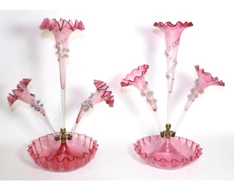 A Cranberry Glass Epergne, with frilled rim, the central trumpet vases flanked by two further vases, on a circular base, 50cm