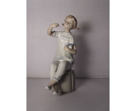 Lladro figure of a seated girl holding a doll, 18cm in height